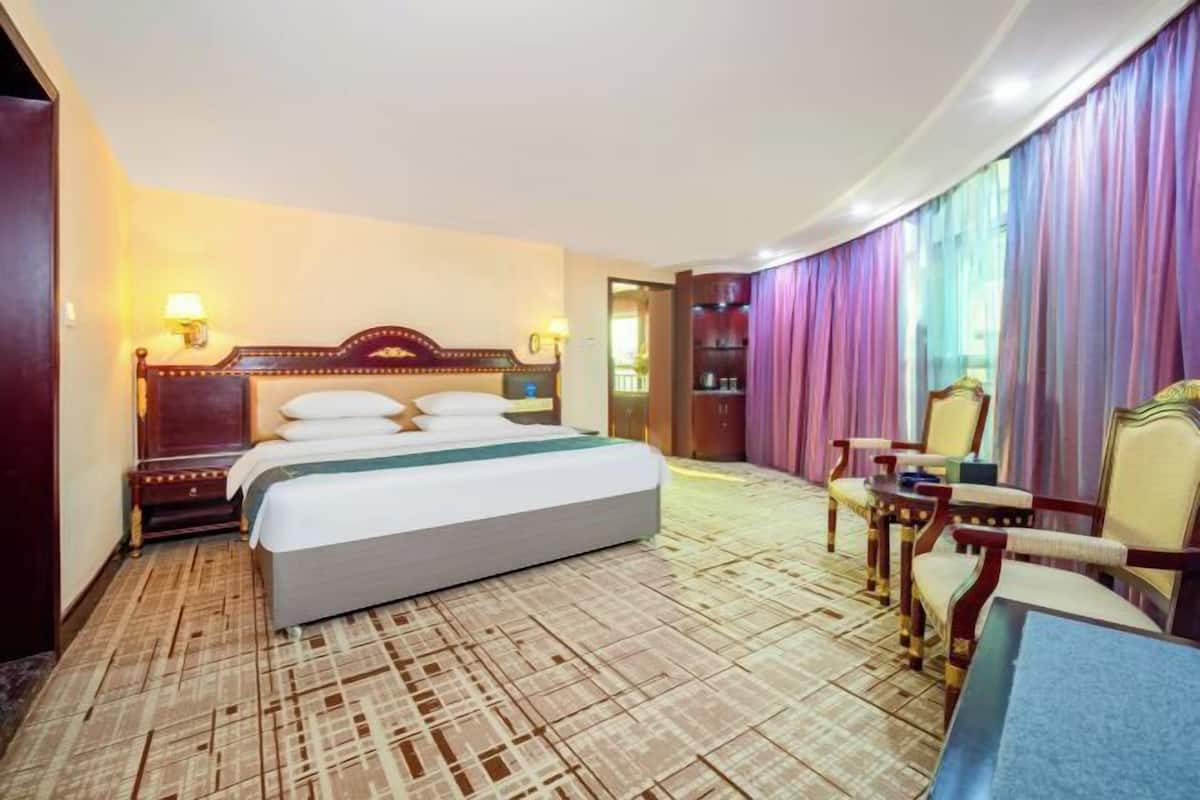 Ein Hotelzimmer mit einem großen Bett, einem Schreibtisch und einem Stuhl.