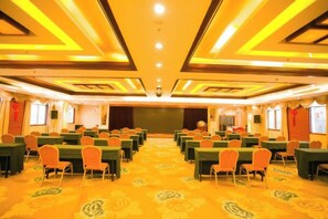 A conference room with rows of tables and chairs, a stage, and a carpeted floor. - Hengsheng Hotel (Baise)