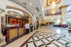 A hotel lobby with a reception desk, a chandelier, and a patterned floor. - Hengsheng Hotel (Baise)