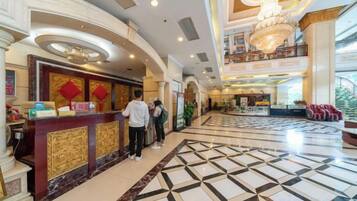 Un vestíbulo de hotel con una recepción, una araña y un mostrador de check-in.