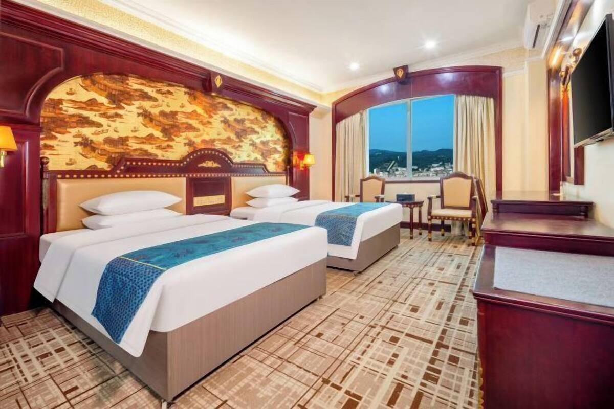 Ein Hotelzimmer mit zwei Betten, einem Schreibtisch und Blick auf die Stadt.