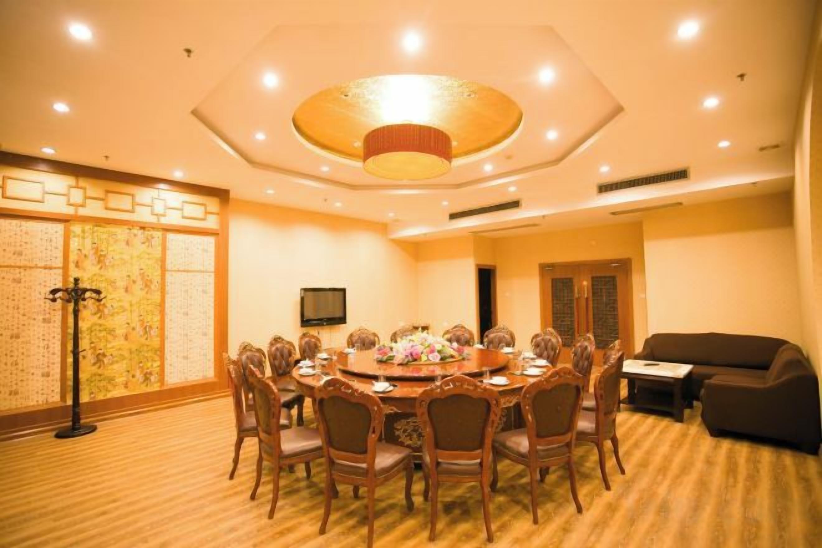 A conference room with a round table, chairs, and a television.
