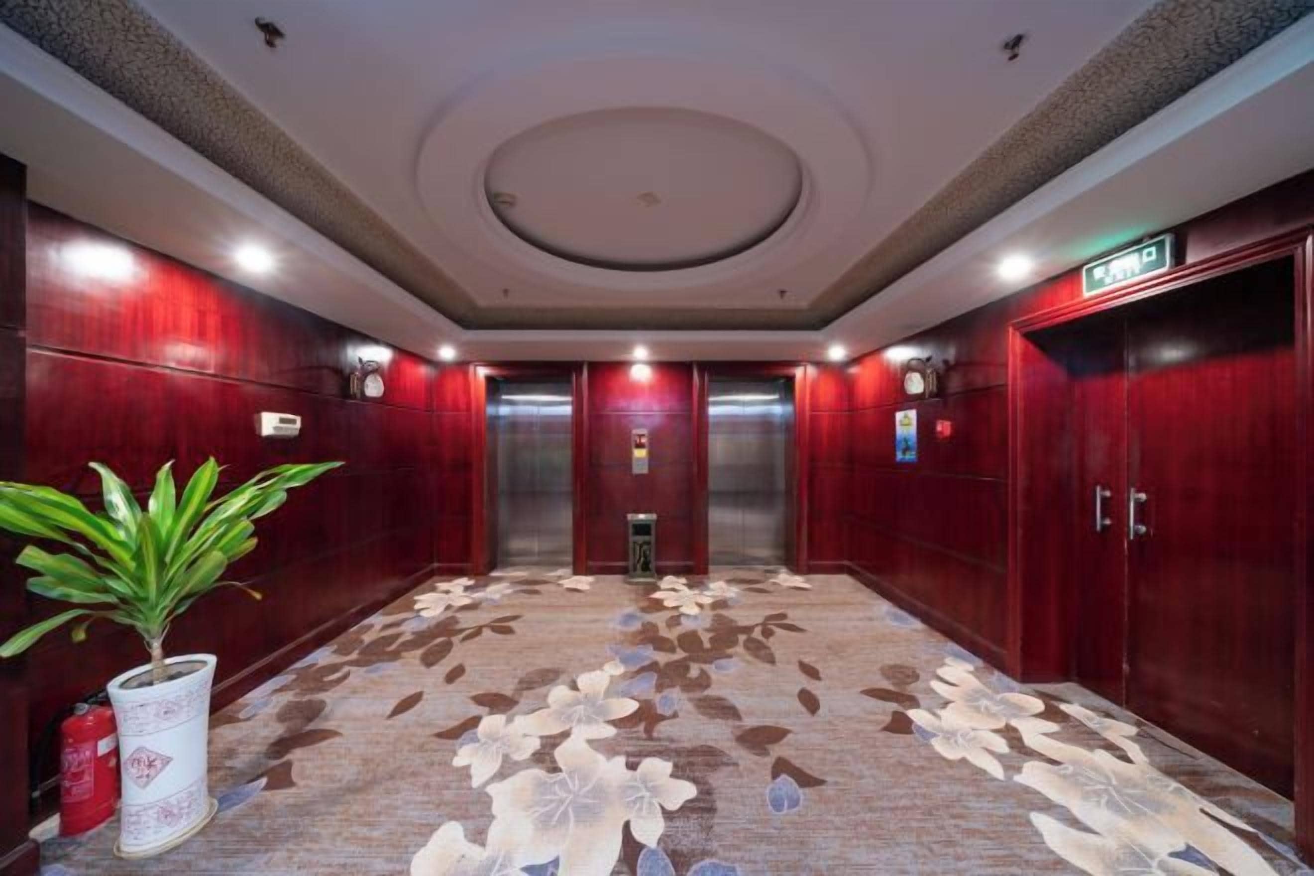 Un'hall d'albergo con tappeto a motivi, pareti in legno e due ascensori.