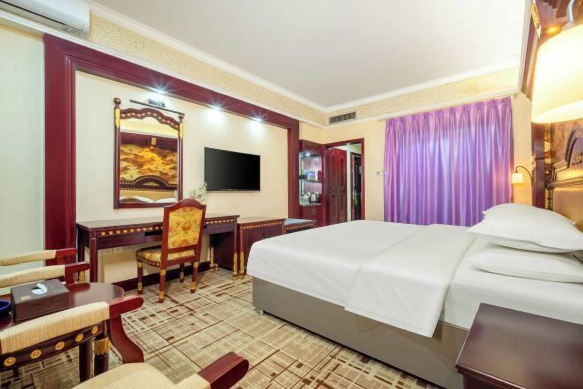 Ein Hotelzimmer mit Bett, Schreibtisch, Stuhl, Fernseher und einer Badezimmertür.