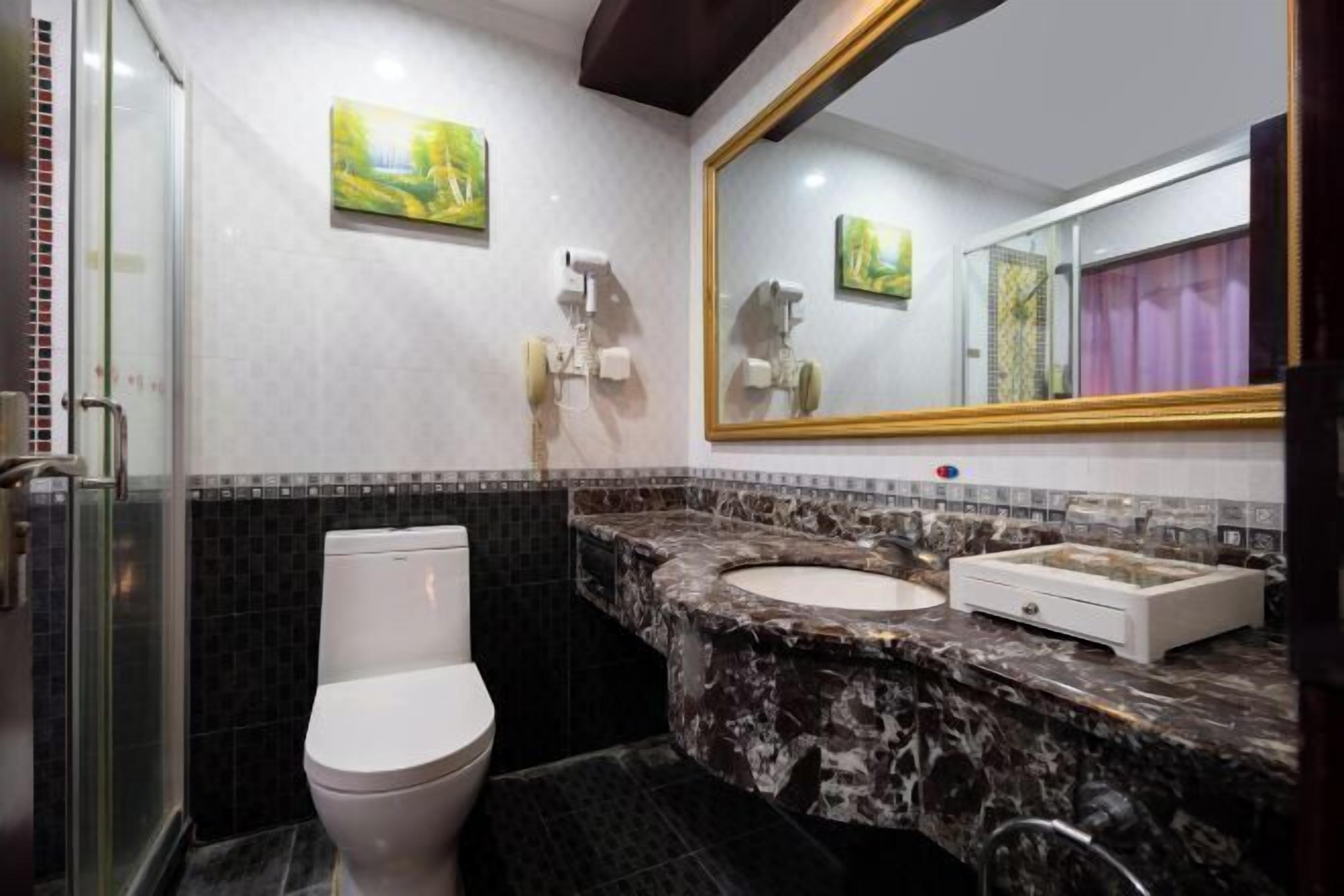 A bathroom with a toilet, a sink, a mirror, and a shower area.
