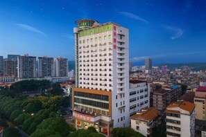 A high-rise hotel with multiple floors, a prominent rooftop structure, and a view of the surrounding cityscape.