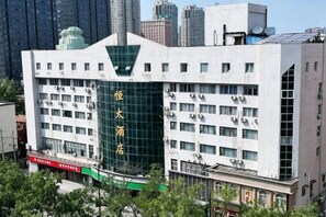 Un edificio moderno con fachada de vidrio verde, varios pisos y una entrada destacada.