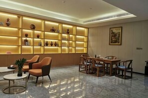 A hotel lobby with a seating area, a wall of illuminated shelves, and a dining table. - Hengtai Hotel (Zhengzhou Zijingshan Street Subway Station) (Zhengzhou)