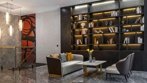 Una hall moderna con pavimento in marmo, un divano, un tavolino da caffè, una libreria e una parete decorativa.