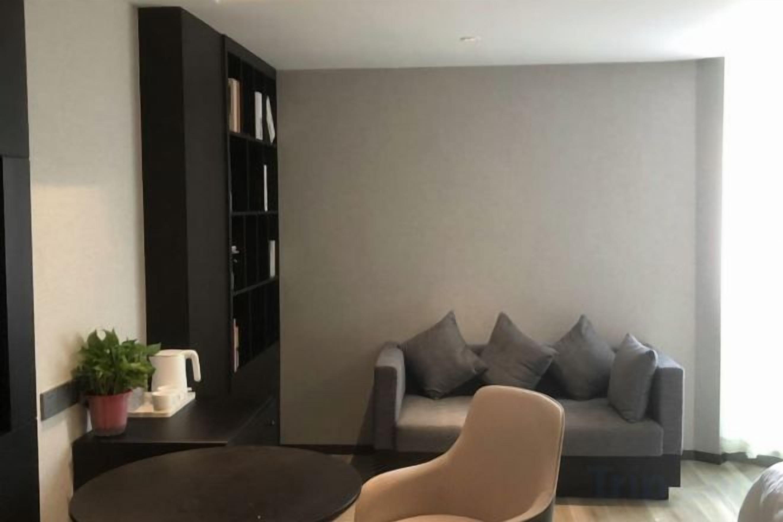 A living room with a grey sofa, a round coffee table, and a bookshelf.