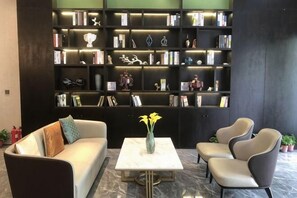 Un espace de vie moderne comprenant un canapé, des fauteuils, une table basse et une grande bibliothèque remplie de livres et d’objets décoratifs.