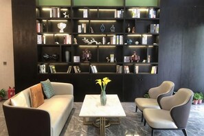 A modern living room with a sofa, armchairs, a coffee table, and a large bookshelf filled with books and decorative items. - Hengtai Hotel (Zhengzhou Zijingshan Street Subway Station) (Zhengzhou)