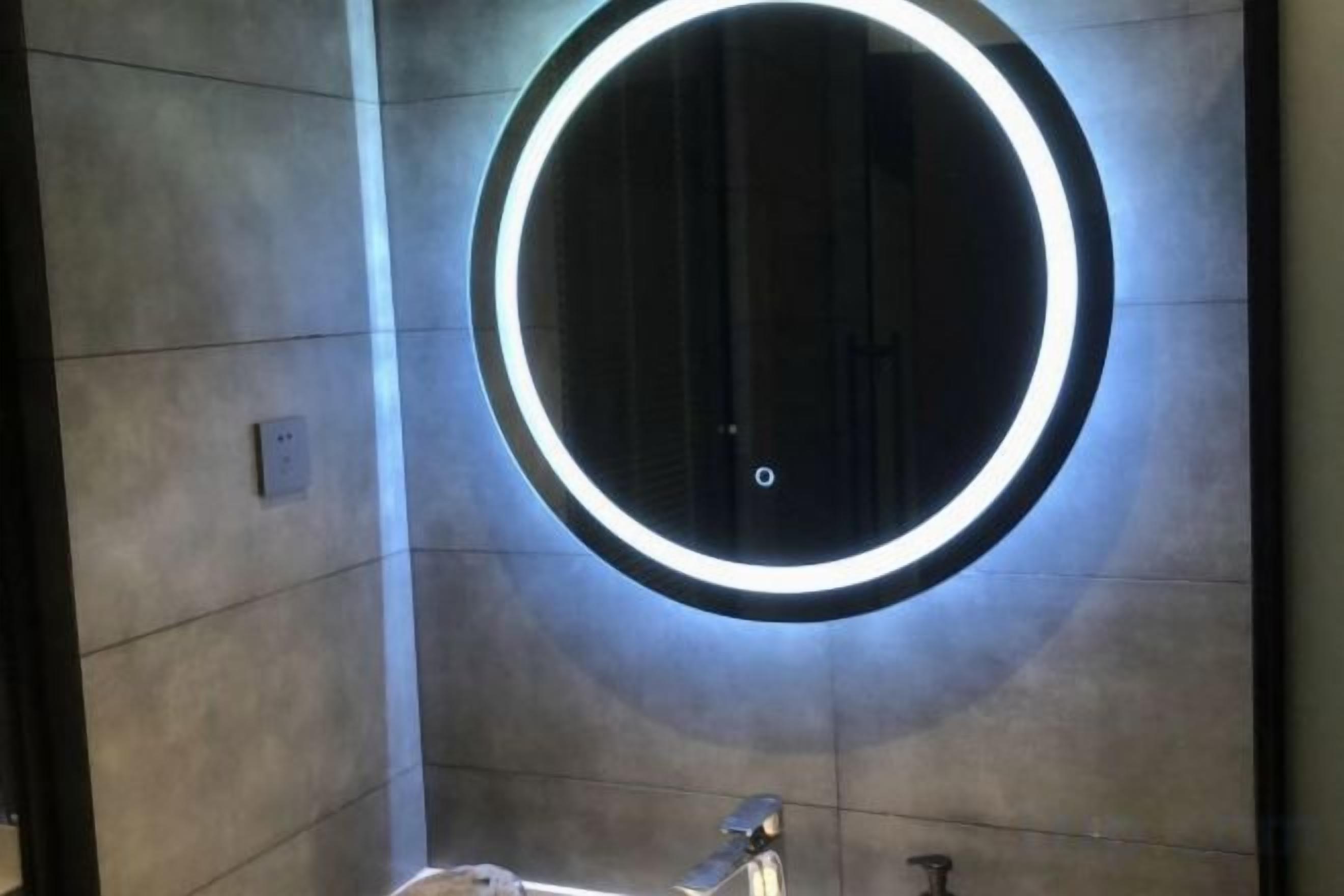 A circular light fixture on a wall, a metallic faucet, and a small, rectangular object on the floor.