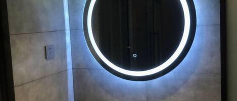 A circular light fixture on a wall, a metallic faucet, and a small, rectangular object on the floor.