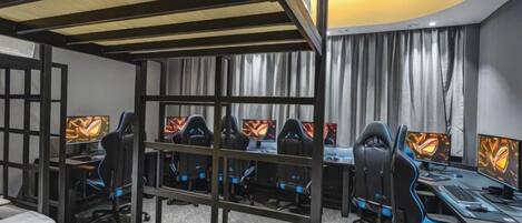 A gaming room with multiple gaming stations, each with a monitor and a chair.