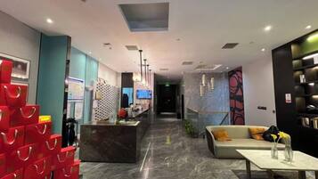 A hotel lobby with a reception desk, seating area, and a coffee station.