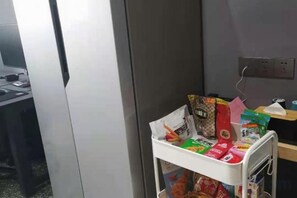 A white metal cart with various items including a red bag, a green box, and a white container. - Hengtai Hotel (Zhengzhou Zijingshan Street Subway Station) (Zhengzhou)