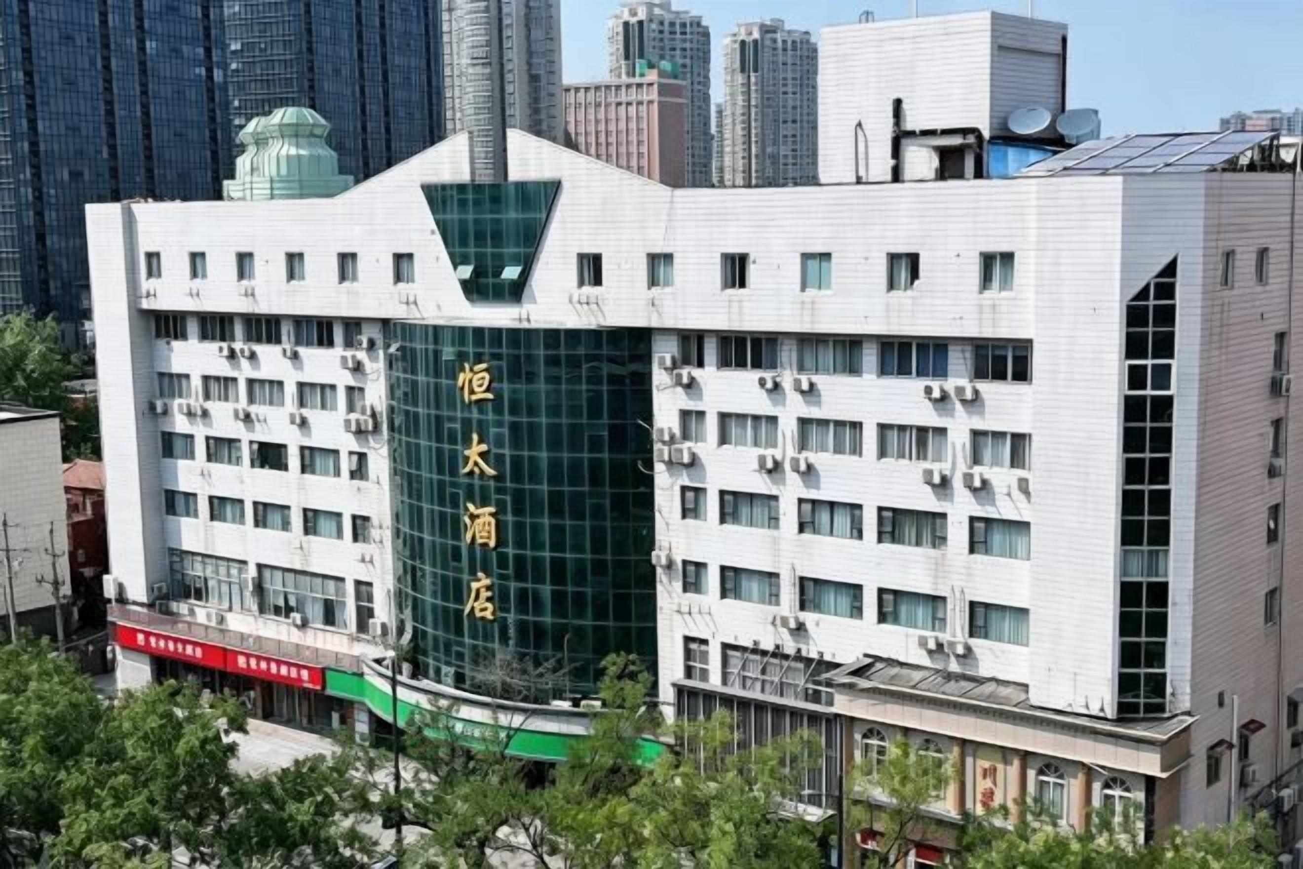 A multi-story building with a prominent green glass facade and a white exterior.