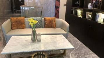Un lobby moderno con un sofá, un jarrón con flores y una mesa de mármol.
