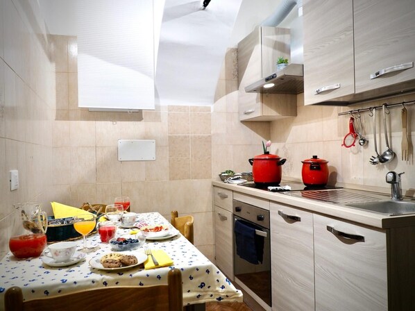 Une cuisine moderne avec une table à manger dressée pour le petit-déjeuner, où l’on trouve une variété de plats et de boissons.