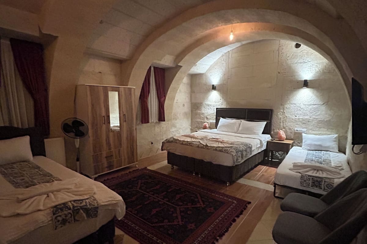 Una habitació acollidora d'arcs, amb dos llits, zona de seients i un ventilador.