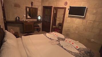 A bedroom with a bed, a dresser, a mirror, and a television mounted on the wall.