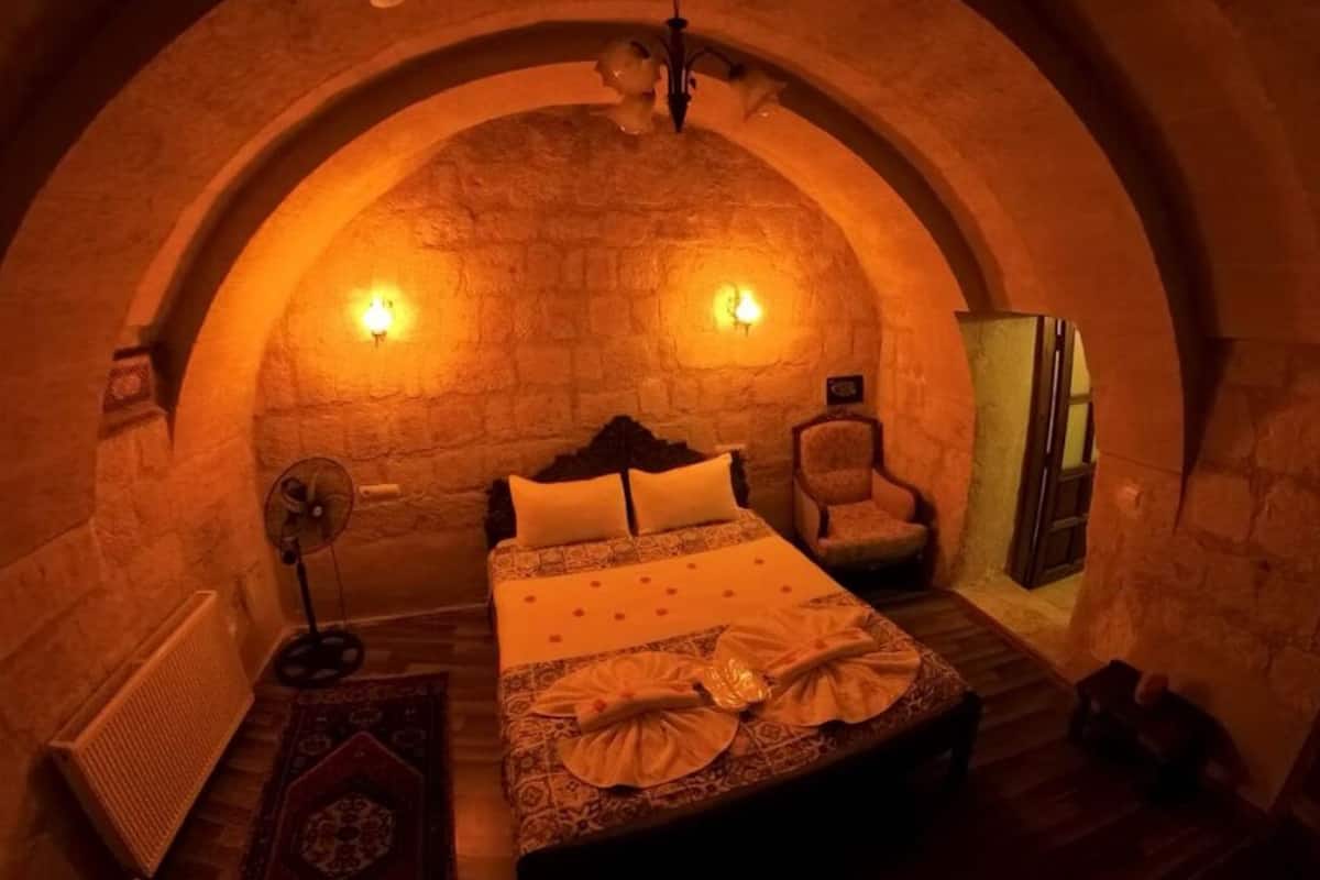 Una habitació acollidora d'arcs, amb un llit, una cadira i un ventilador.