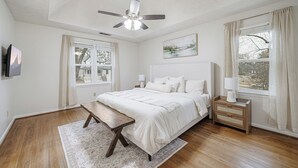 Ein Schlafzimmer mit Bett, Nachttisch, Lampe und Deckenventilator.