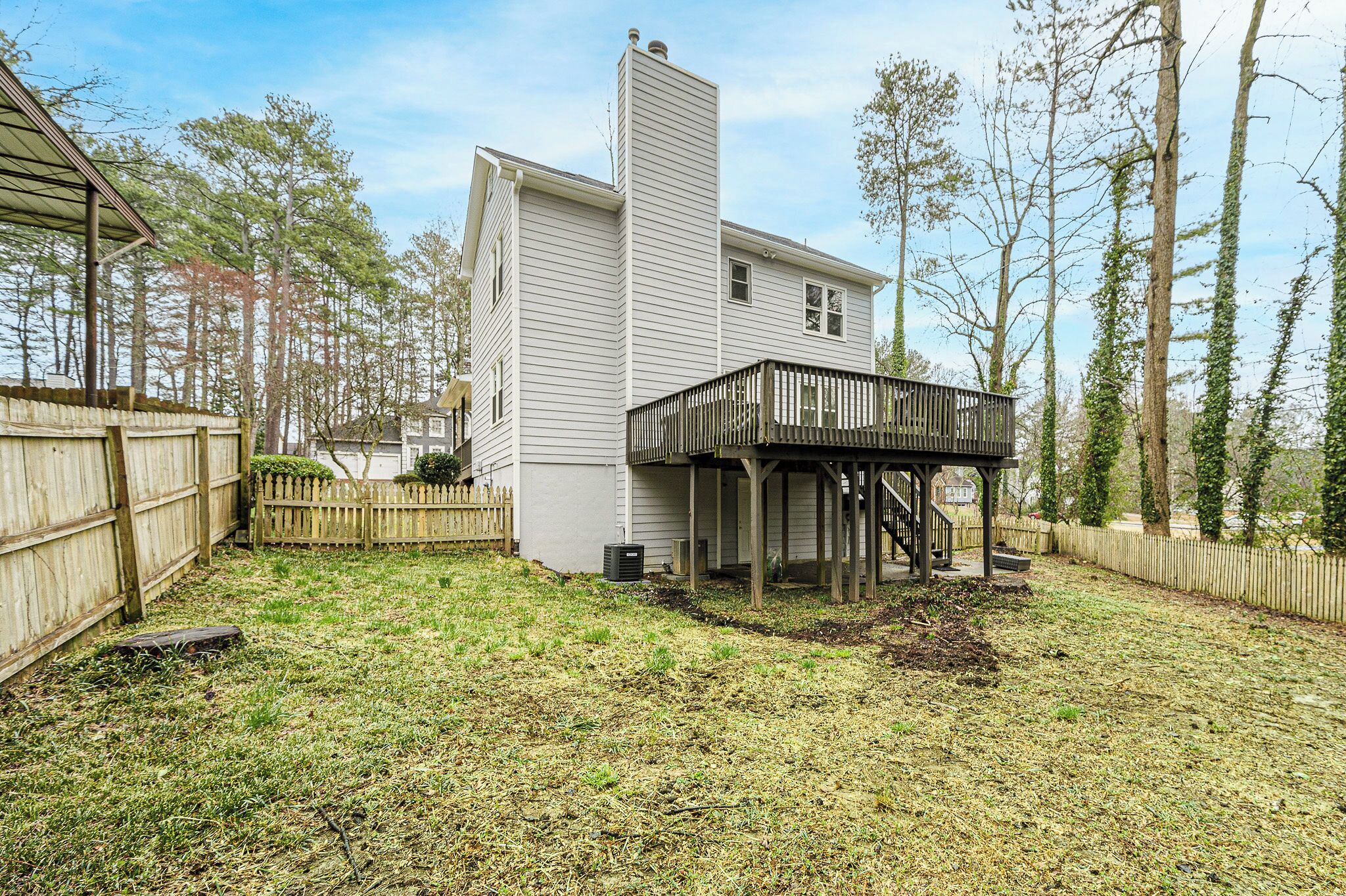 A house with a covered deck and a fenced backyard.