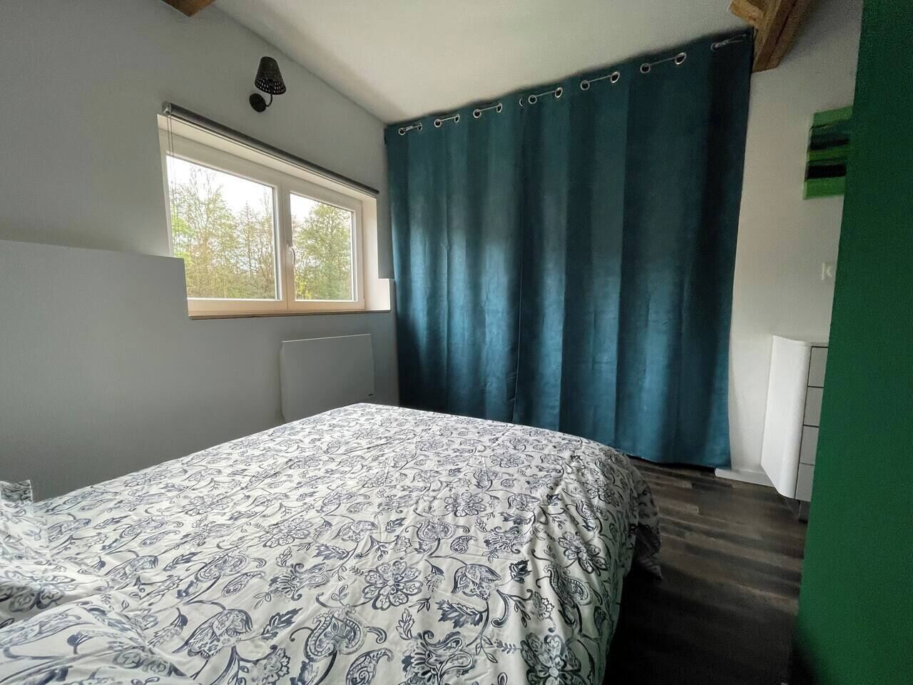 Quarto com cama, janela e cortina.