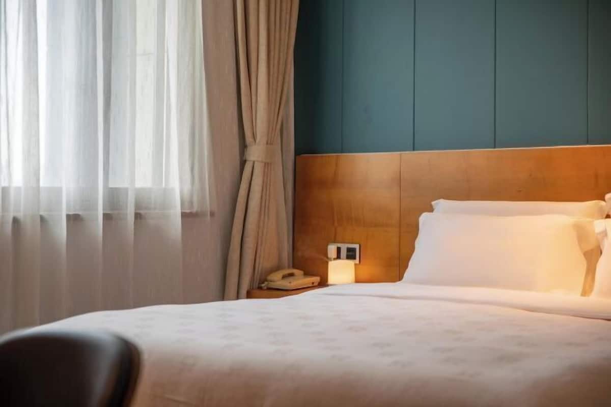 Une chambre d’hôtel avec une tête de lit en bois, une table de chevet avec une lampe et un téléphone.