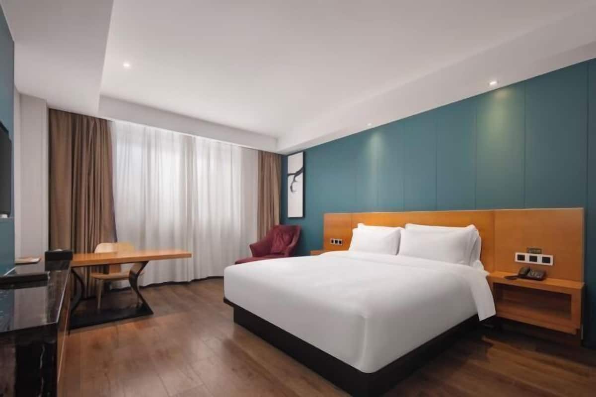 Une chambre d’hôtel moderne, dotée d’un grand lit, d’un bureau et d’une chaise.