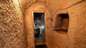 Un estrecho pasillo de paredes de piedra con una puerta que da a una habitación.