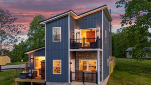 A two-story house with a balcony on the upper floor, a deck with outdoor seating, and a view of the surrounding greenery. - Serenity Villa: Luxurious Retreat with Hot Tub, Rooftop Deck & Mountain View's (Sharps Chapel)