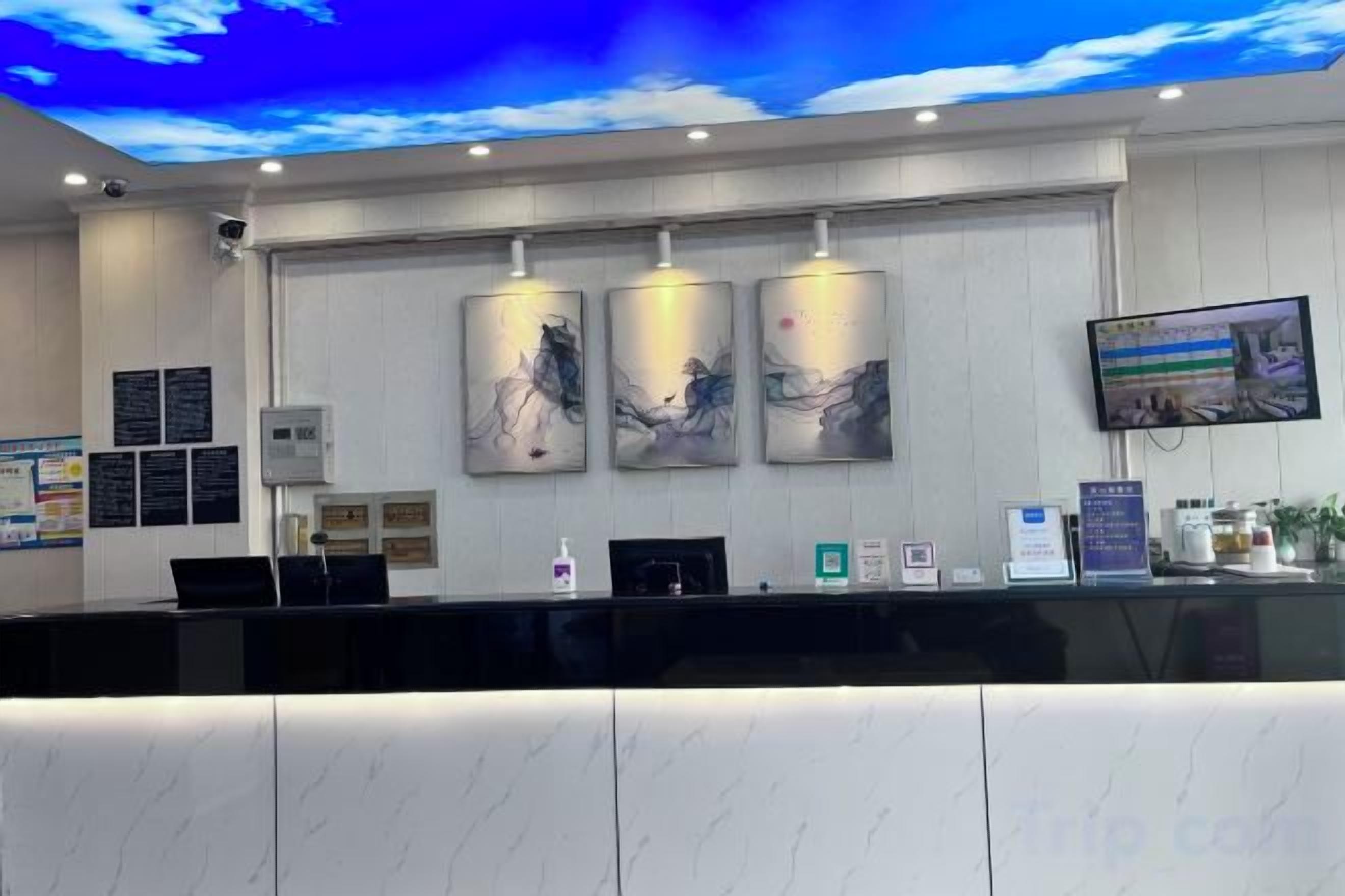 A reception desk with a marble counter, three framed artworks above it, and a television screen on the wall.