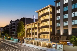 A multi-story hotel with a modern facade, illuminated windows, and signage for a hotel and a restaurant. - Yide Hotel (Yingde Pearl Plaza Pedestrian Street) (Yingde)