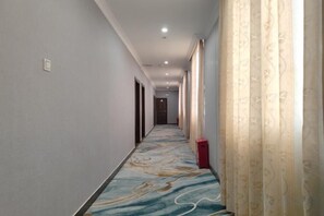 A hotel corridor with a patterned carpet, doors on both sides, and a red trash bin. - Yide Hotel (Yingde Pearl Plaza Pedestrian Street) (Yingde)