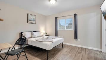 Une chambre à coucher avec un lit, une chaise, une fenêtre et un tableau accroché au mur.