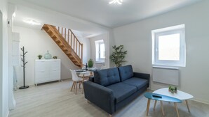 Een moderne woonkamer met een bank, eettafel en een trap.