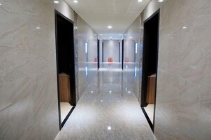Un pasillo con piso reflectante y paredes de mármol que conduce a una habitación con puerta.