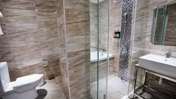 Un baño moderno con ducha envuelta en vidrio, inodoro blanco y tocador con espejo.