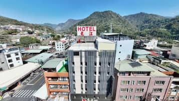 A hotel with a prominent sign, surrounded by buildings and a mountainous backdrop.