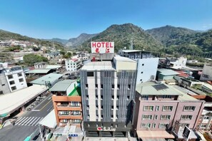 A hotel with a prominent sign, surrounded by buildings and a mountainous backdrop. - Dragon River Hotel (Nantou)