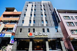 A multi-story hotel building with a modern facade, featuring a prominent logo and signage for the Dragon River Hotel.