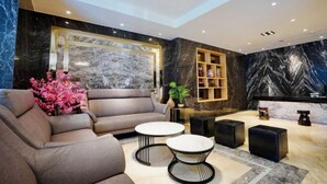 A modern living room with a sofa, two round tables, and a decorative plant. - Dragon River Hotel (Nantou)