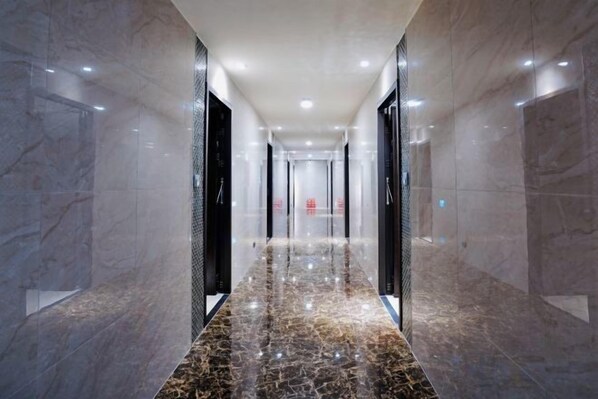 A corridor with marble flooring and walls, leading to a door with a red sign. - Dragon River Hotel (Nantou)