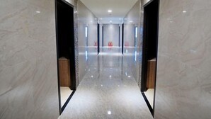 A modern, well-lit hallway with marble flooring and walls, leading to a central area with a reflective floor. - Dragon River Hotel (Nantou)