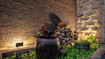 Un muro de piedra con una fuente de agua, que incluye una maceta grande y una fuente pequeña.