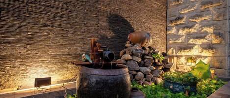 A stone wall with a water feature, including a large pot and a small fountain.