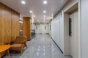A hallway with a wooden wall, a chair, a table, and a door at the end. - Bonilyi Hotel (Ningbo Beilun Yintai City ) (Ningbo)